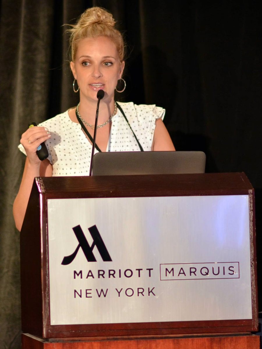 Ashley speaking at a podium at the Marriott Marquis in New York