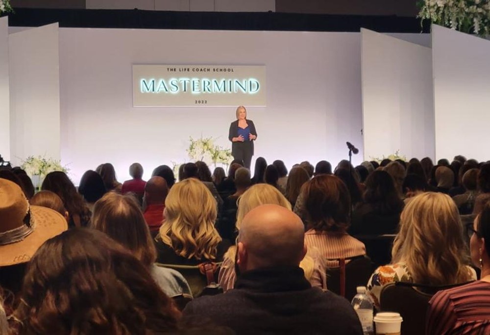 Ashley on stage at The Life Coach School Mastermind in front of a large audience